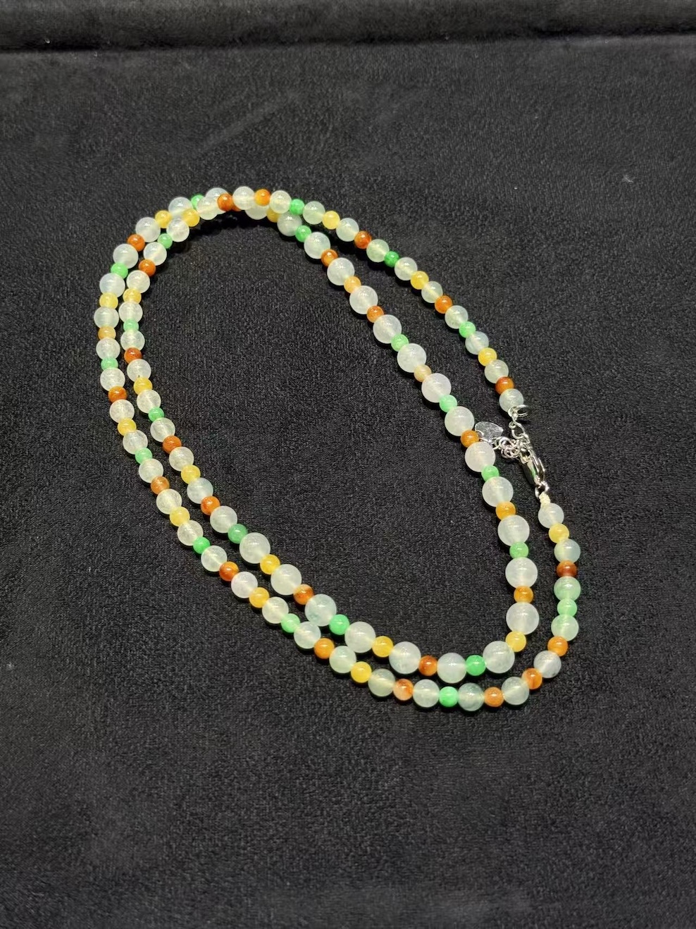Multi-colour jadeite necklace strung with icy translucent jadeite beads and smaller vibrant green, yellow, and orange-red jade spacer beads