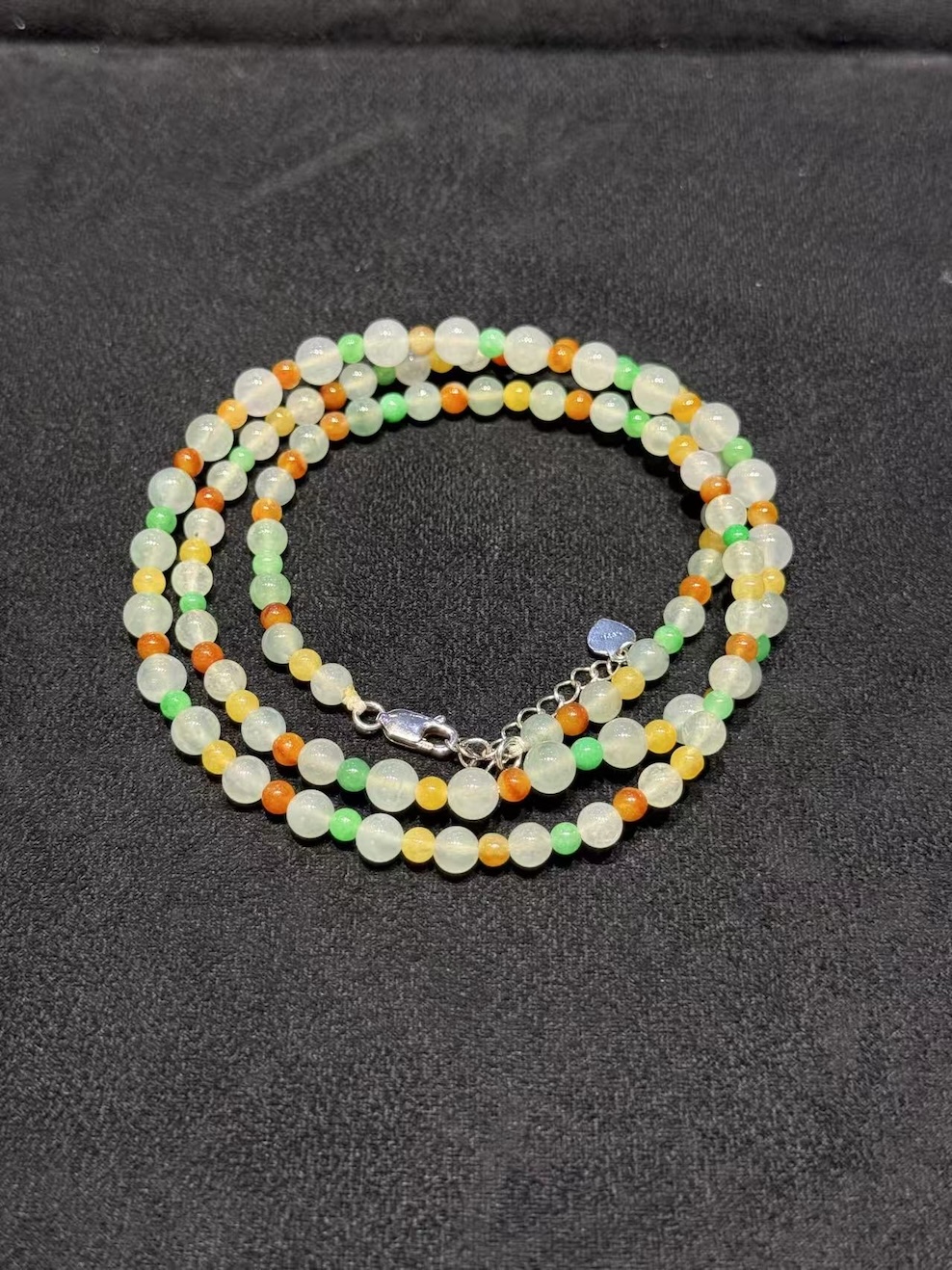 Multi-colour jadeite necklace strung with icy translucent jadeite beads and smaller vibrant green, yellow, and orange-red jade spacer beads