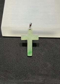 Jade cross pendant carved from translucent icy jadeite with vibrant green floating-flower patches, hung from a small 18k white gold bail
