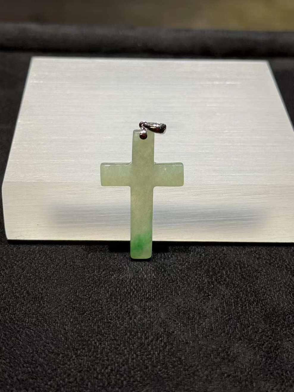 Jade cross pendant carved from translucent icy jadeite with vibrant green floating-flower patches, hung from a small 18k white gold bail