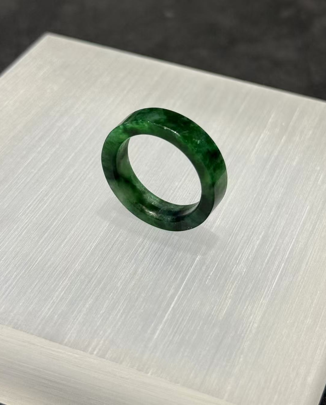 Old pit jadeite ring carved as a solid band from a single piece of translucent vibrant green jadeite with deeper green patches and natural variation