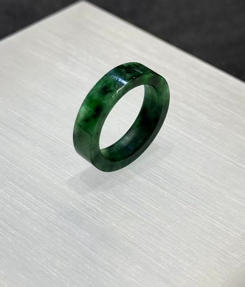 Old pit jadeite ring carved as a solid band from a single piece of translucent vibrant green jadeite with deeper green patches and natural variation