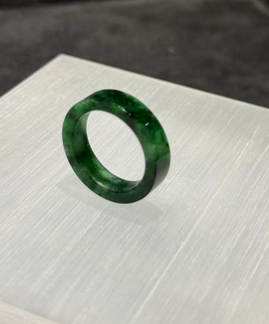 Old pit jadeite ring carved as a solid band from a single piece of translucent vibrant green jadeite with deeper green patches and natural variation