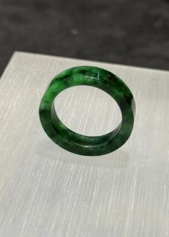 Old pit jadeite ring carved as a solid band from a single piece of translucent vibrant green jadeite with deeper green patches and natural variation