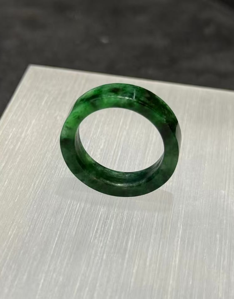 Old pit jadeite ring carved as a solid band from a single piece of translucent vibrant green jadeite with deeper green patches and natural variation