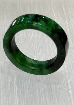 Old pit jadeite ring carved as a solid band from a single piece of translucent vibrant green jadeite with deeper green patches and natural variation