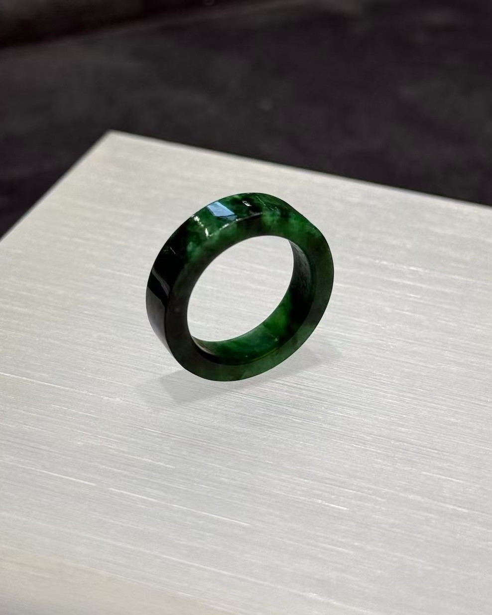 Old pit jadeite ring carved as a solid band from a single piece of translucent vibrant green jadeite with deeper green patches and natural variation