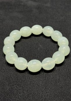 Icy jadeite bracelet strung with round translucent jadeite beads in a very faint, near-colourless green tone, shown on a dark display cloth