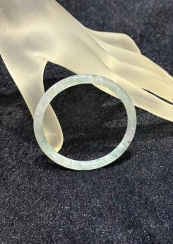 Floral green jade bangle in a translucent near-colourless body with soft green floating flower patches drifting through the ring