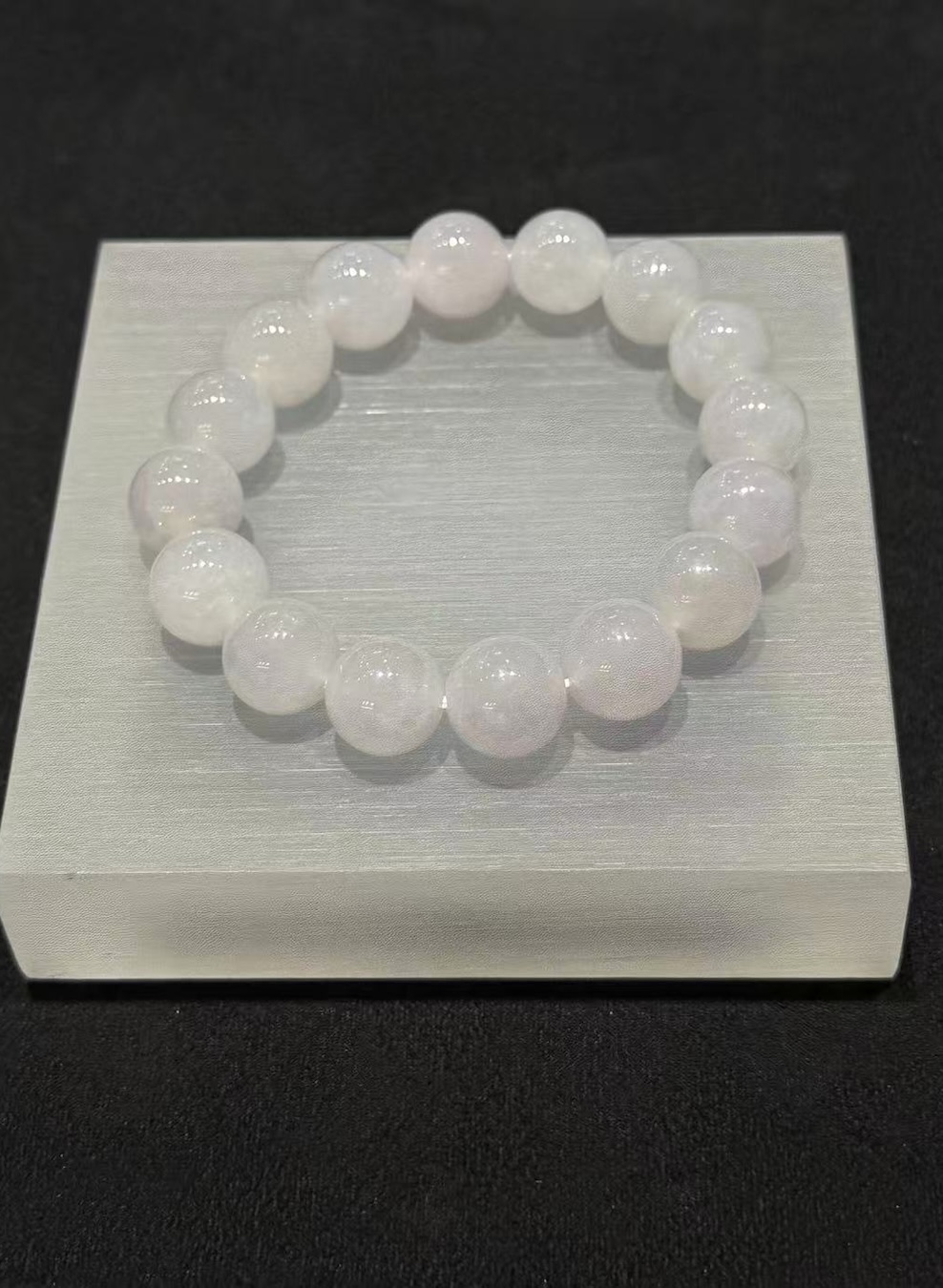 Lavender jade bracelet strung with round icy translucent jadeite beads in a whiteish body with a very faint lavender tint