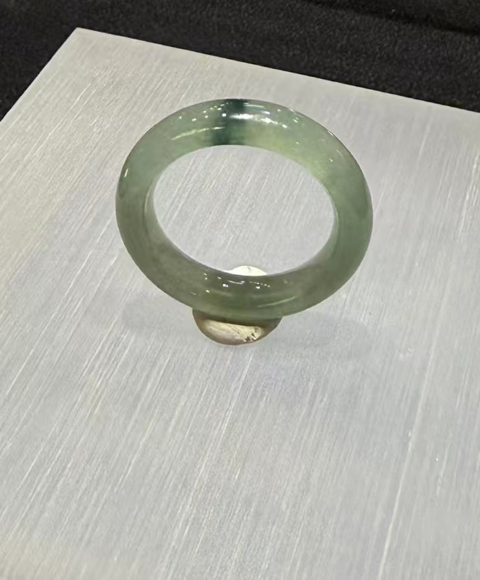 Translucent jadeite ring carved as a solid band from an icy, highly translucent jadeite with a faint green tone and a small floating-flower patch at the top