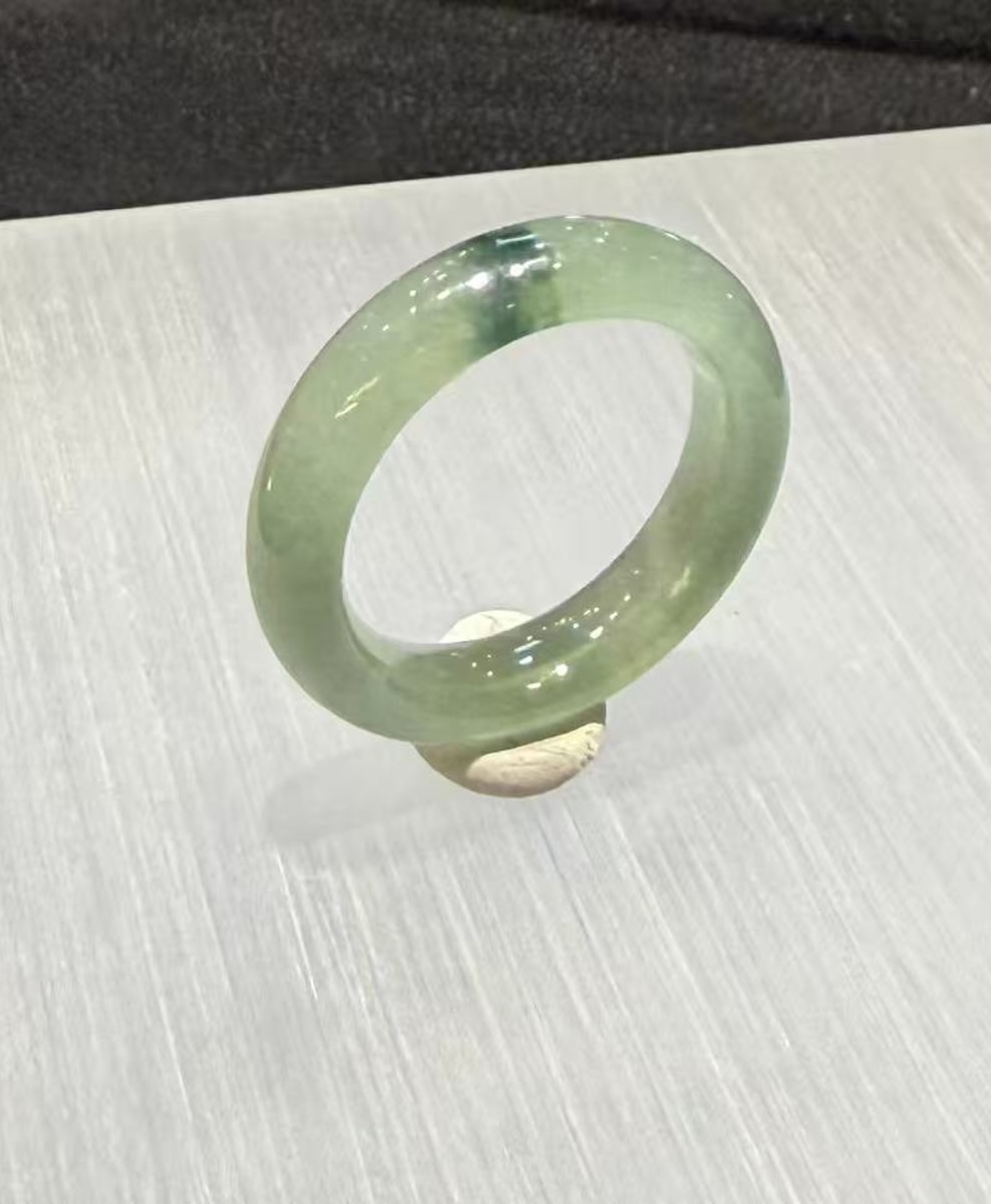 Translucent jadeite ring carved as a solid band from an icy, highly translucent jadeite with a faint green tone and a small floating-flower patch at the top