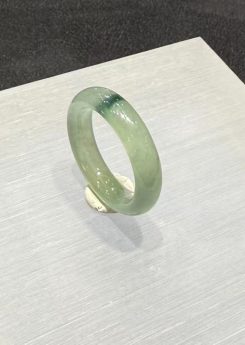 Translucent jadeite ring carved as a solid band from an icy, highly translucent jadeite with a faint green tone and a small floating-flower patch at the top