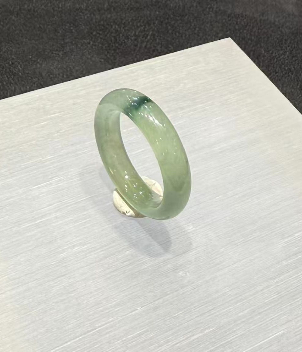 Translucent jadeite ring carved as a solid band from an icy, highly translucent jadeite with a faint green tone and a small floating-flower patch at the top