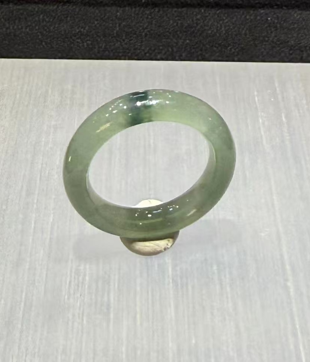 Translucent jadeite ring carved as a solid band from an icy, highly translucent jadeite with a faint green tone and a small floating-flower patch at the top