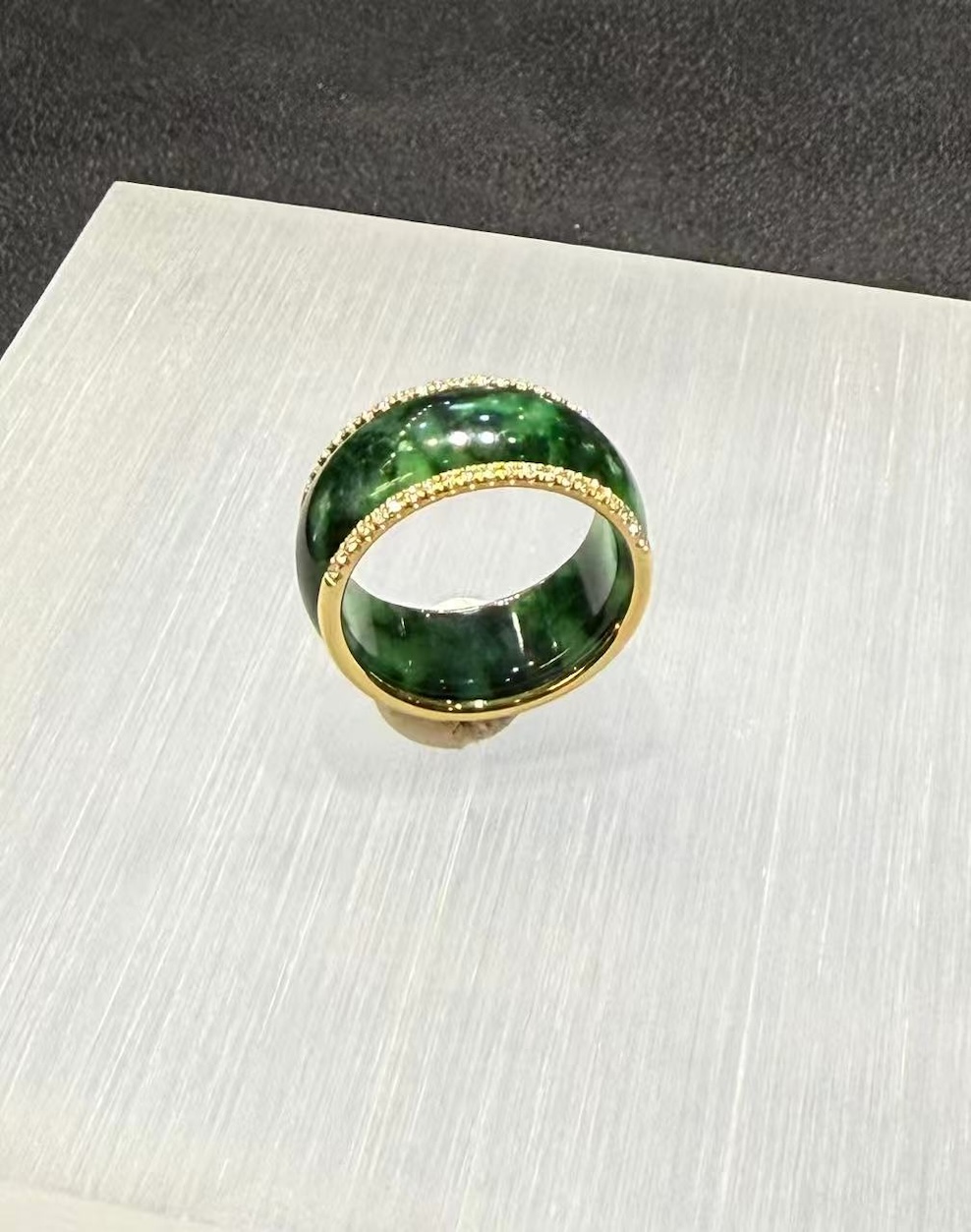 Green jadeite diamond ring in a deep translucent old pit green, set with a channel of small diamonds around the middle and lined with 18k yellow gold on the inside
