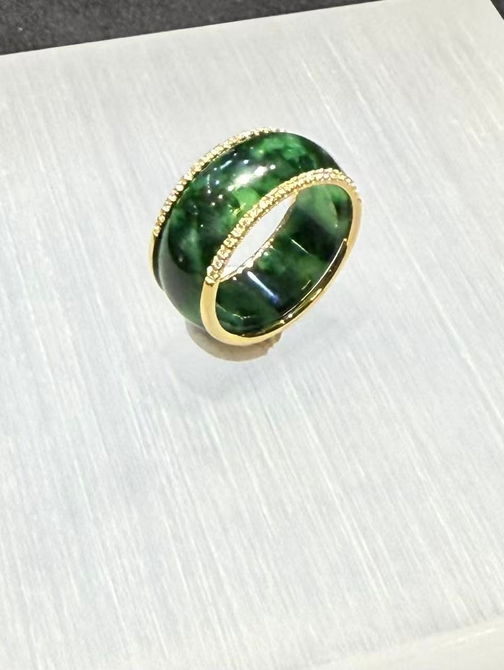 Green jadeite diamond ring in a deep translucent old pit green, set with a channel of small diamonds around the middle and lined with 18k yellow gold on the inside