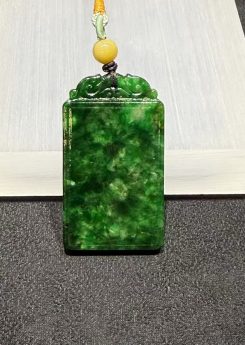 Old pit jadeite pendant carved as a rectangular pai-zi plaque from translucent vibrant deep green jadeite, with carved openwork scrollwork at the top and a smooth uncarved main face