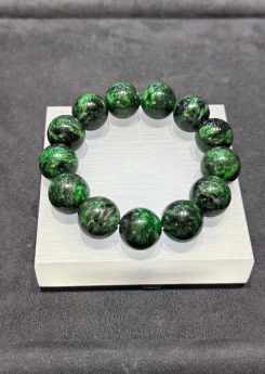 Vibrant green jadeite bracelet strung with large round beads showing deep dark green patches drifting through the vibrant green base