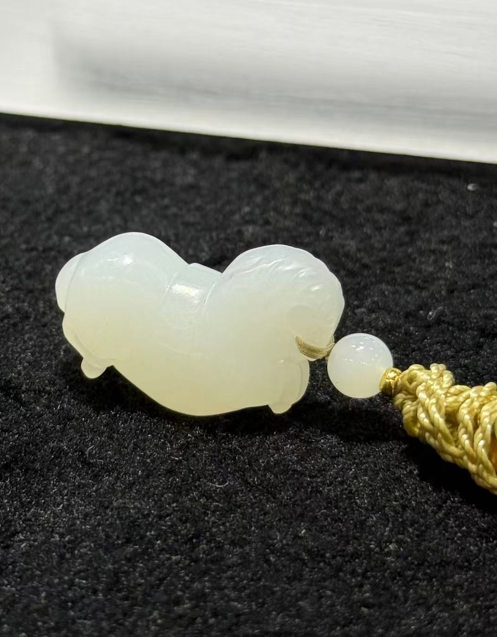 Jade horse pendant hand-carved from creamy white nephrite in the traditional Chinese Tang horse (唐马) style, hung from a small braided cord with a jade bead