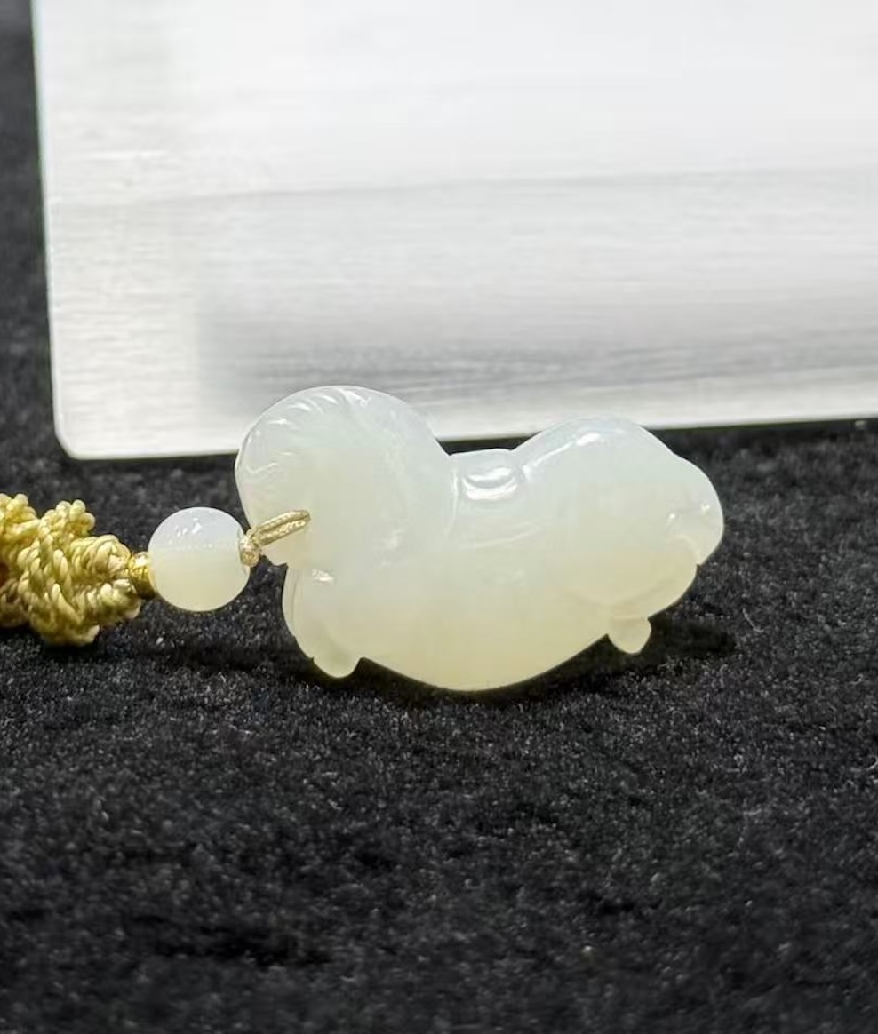 Jade horse pendant hand-carved from creamy white nephrite in the traditional Chinese Tang horse (唐马) style, hung from a small braided cord with a jade bead