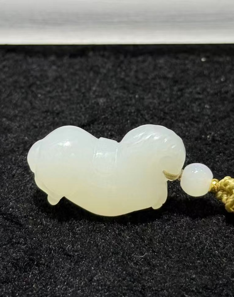 Jade horse pendant hand-carved from creamy white nephrite in the traditional Chinese Tang horse (唐马) style, hung from a small braided cord with a jade bead