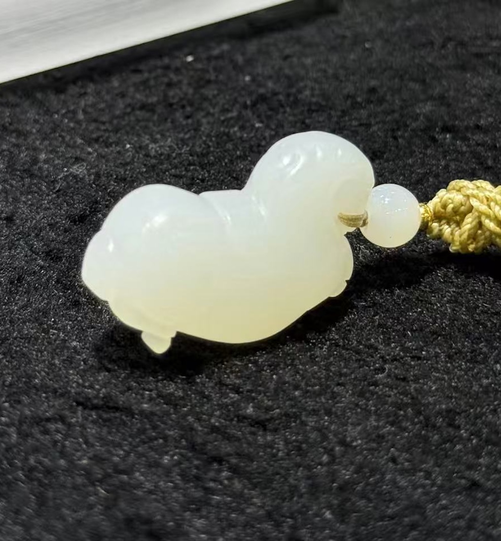 Jade horse pendant hand-carved from creamy white nephrite in the traditional Chinese Tang horse (唐马) style, hung from a small braided cord with a jade bead