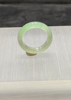 Faint green jadeite ring carved as a slim solid band from icy, highly translucent jadeite in a soft, uniform pale green tone