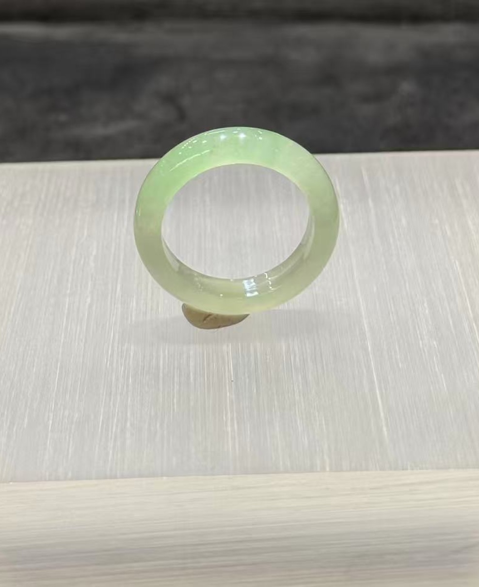 Faint green jadeite ring carved as a slim solid band from icy, highly translucent jadeite in a soft, uniform pale green tone