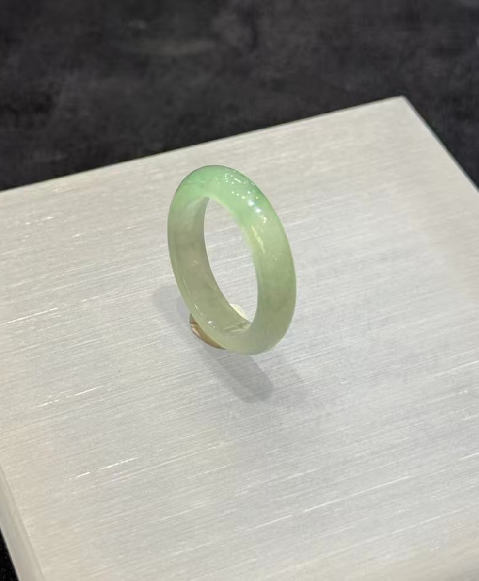 Faint green jadeite ring carved as a slim solid band from icy, highly translucent jadeite in a soft, uniform pale green tone