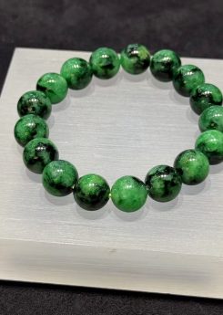Old pit jadeite bracelet strung with large round beads in a translucent, vibrant deep green with darker patches and natural markings