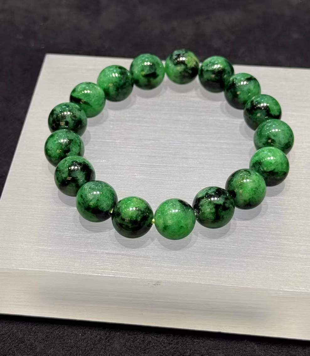 Old pit jadeite bracelet strung with large round beads in a translucent, vibrant deep green with darker patches and natural markings