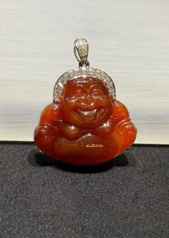 Laughing buddha jade pendant carved from translucent brownish red jadeite showing a smiling Buddha with a round belly, set in an 18k white gold bail with small diamonds