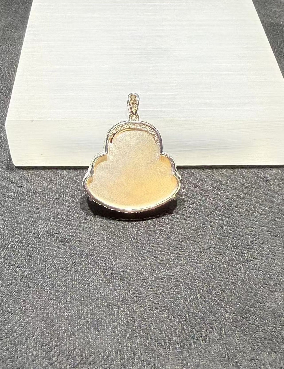 Laughing buddha jade pendant carved from translucent brownish red jadeite showing a smiling Buddha with a round belly, set in an 18k white gold bail with small diamonds