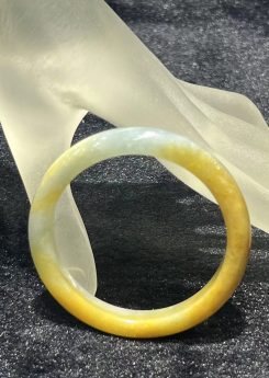 Honey jade bangle in a translucent, warm honey-yellow jadeite with a lighter near-colourless section near the top of the ring