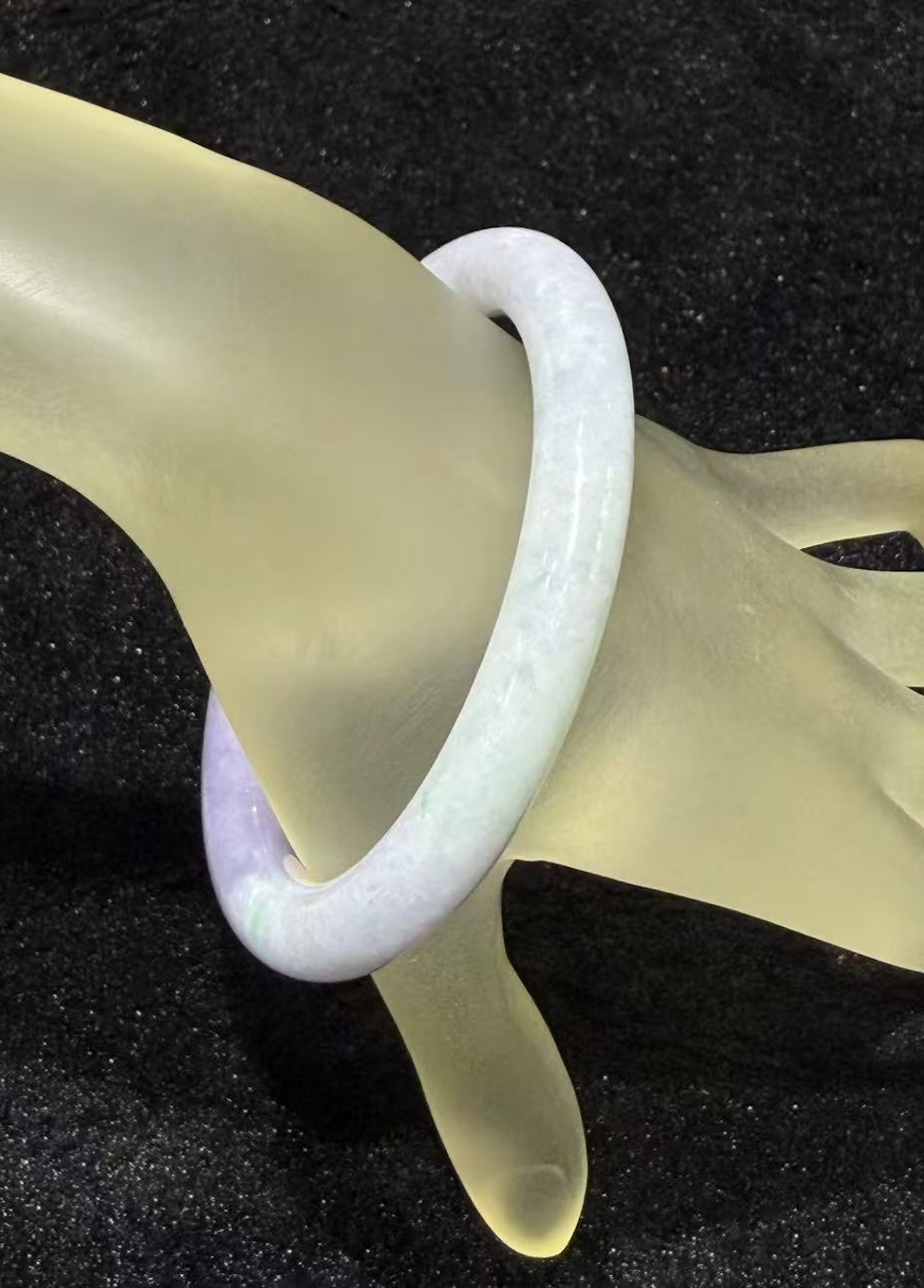 Lavender jade bangle in a translucent lavender body with faint green patches drifting through the ring, carved in a round cut