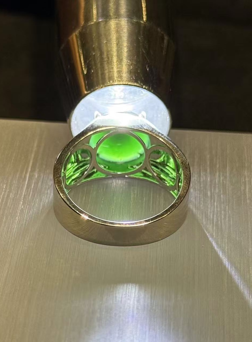 Omphacite jade ring with a translucent black mo cui cabochon that reads pure black under normal light and glows translucent green under torchlight, set in a wide 18k white gold band