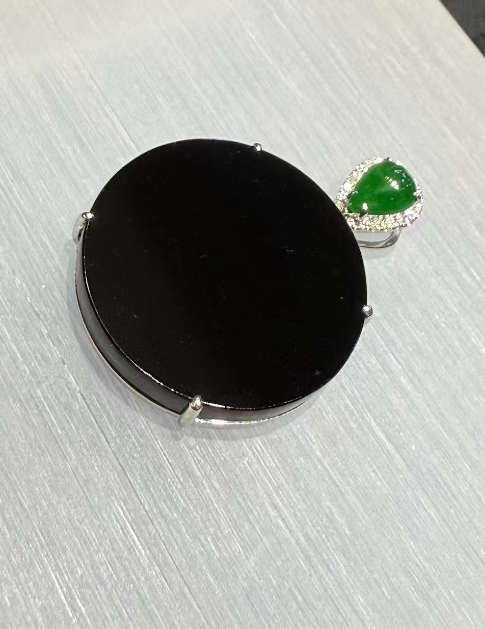 Omphacite jade ring with a translucent black mo cui cabochon that reads pure black under normal light and glows translucent green under torchlight, set in a wide 18k white gold band