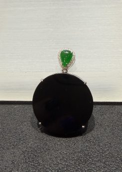 Omphacite jade ring with a translucent black mo cui cabochon that reads pure black under normal light and glows translucent green under torchlight, set in a wide 18k white gold band