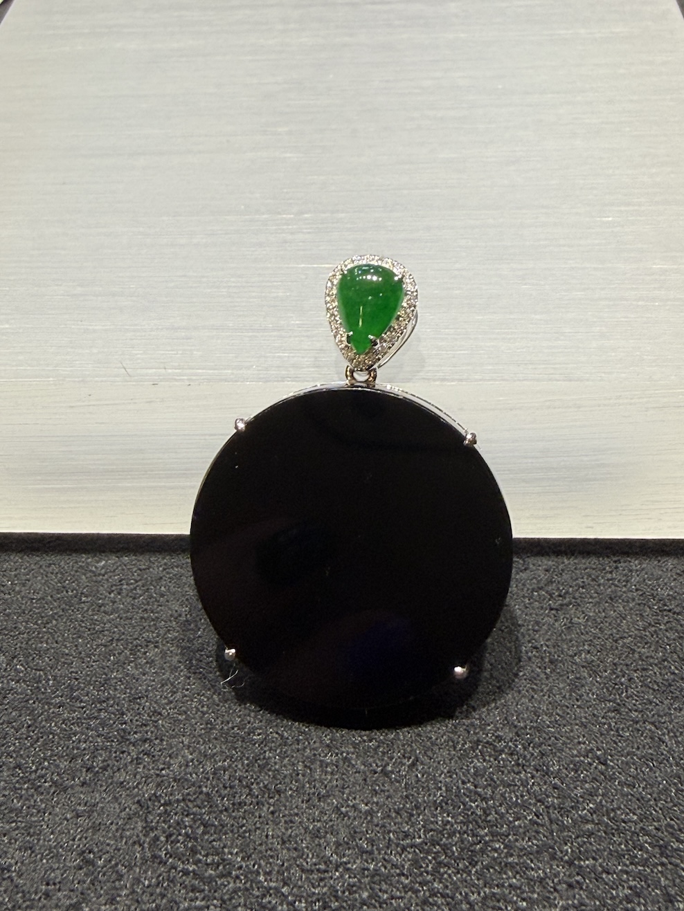 Omphacite jade ring with a translucent black mo cui cabochon that reads pure black under normal light and glows translucent green under torchlight, set in a wide 18k white gold band
