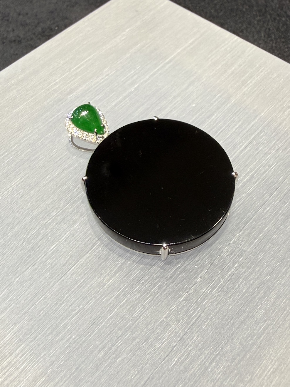 Omphacite jade ring with a translucent black mo cui cabochon that reads pure black under normal light and glows translucent green under torchlight, set in a wide 18k white gold band