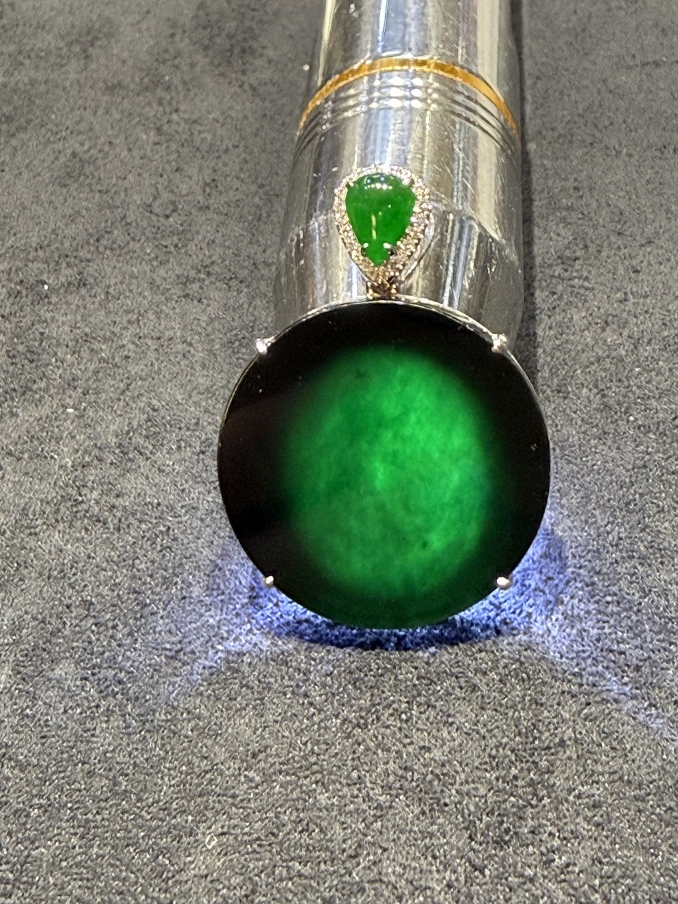 Omphacite jade ring with a translucent black mo cui cabochon that reads pure black under normal light and glows translucent green under torchlight, set in a wide 18k white gold band